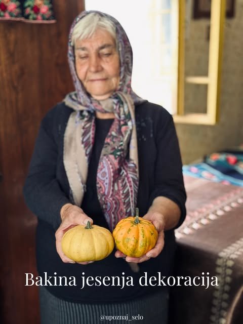 Baka u marami drži dve šarene ukrasne tikvice u seoskoj sobi