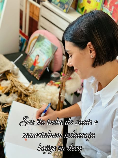 Nevena Jovičić piše za radnim stolom, okružena svojim knjigama za decu